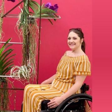 Megan Collins, spinal cord injury survivor, smiles while seated in her wheelchair